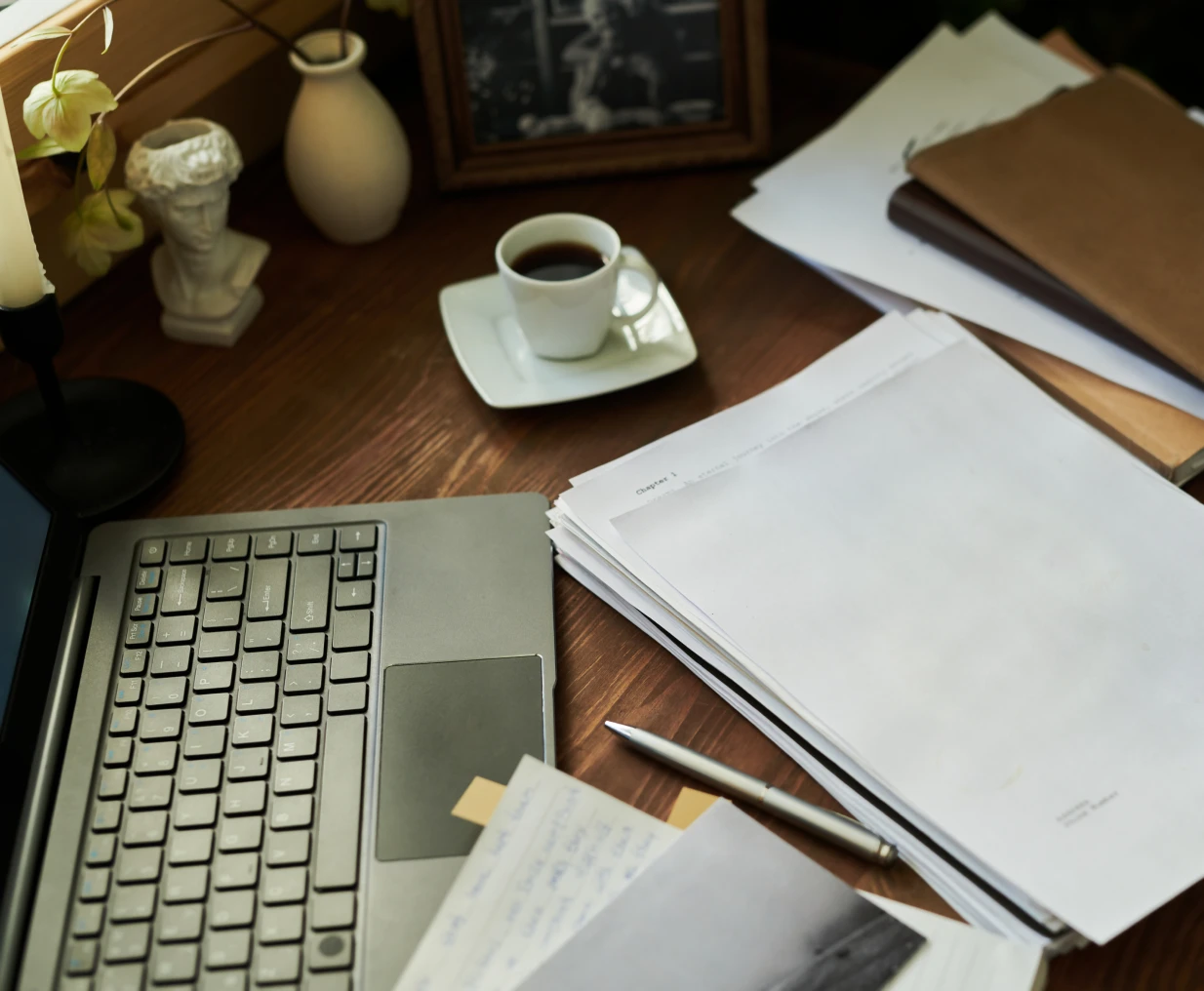 Laptop, papers, and coffee on wooden desk.