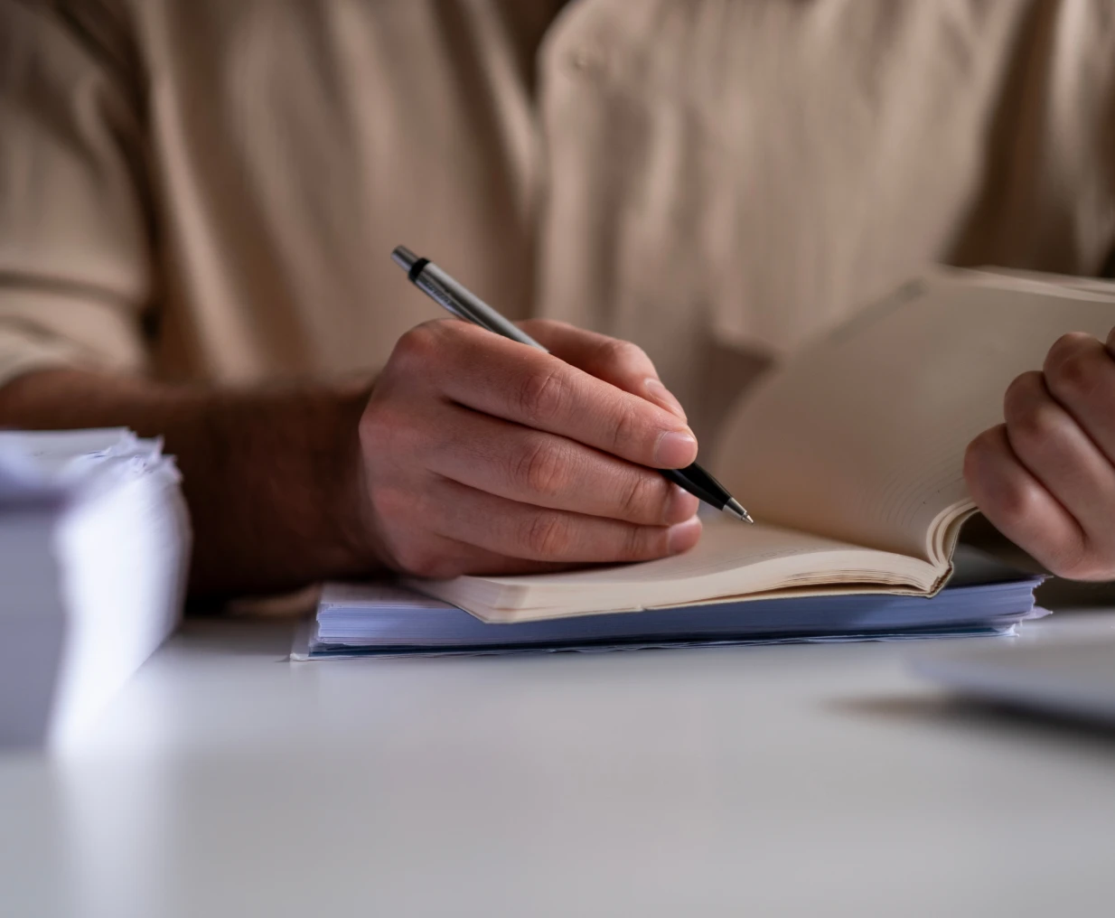 Person writing in a notebook with pen.