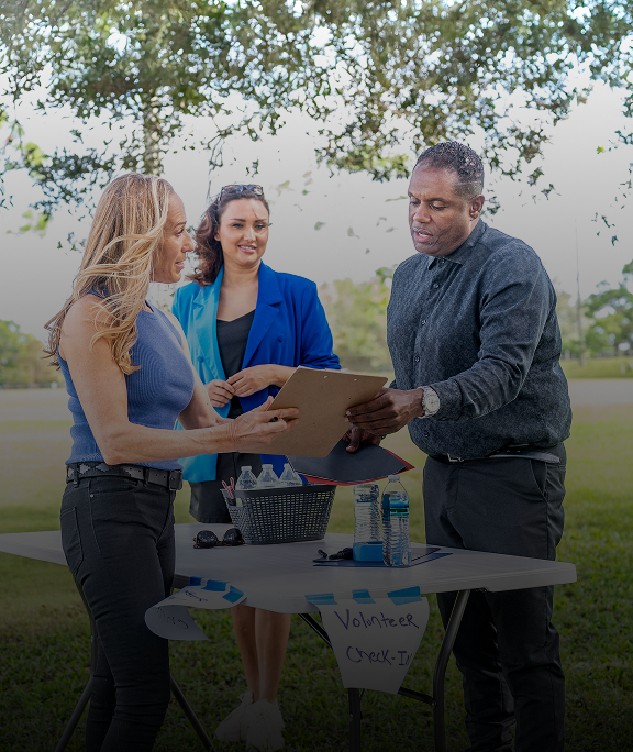 People discussing paperwork at outdoor table.